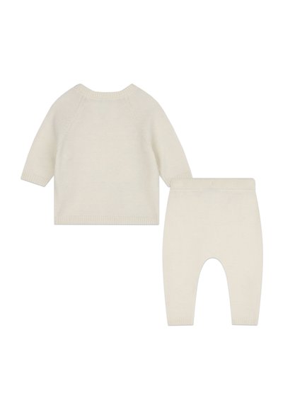 Lichtcreme trui en bijpassende broek gemaakt van zachte stof, met ribgebreide manchetten en zoom, en een eenvoudig, minimalistisch ontwerp.