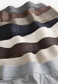 Sous-vêtements masculins assortis dans différentes teintes, présentant des ceintures élastiques flexibles avec le mot "NEXT" subtilement embossé.