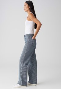 Pantalons larges à motif rayé bleu et blanc, fabriqués dans un tissu à la texture douce, avec des poches avant et une taille haute.