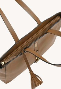 Sac fourre-tout en cuir marron avec longues anses, fermeture éclair et détail en frange. Présente une texture lisse et des bords noirs contrastants.