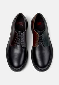Schwarze Lederschuhe mit kontrastierenden Oberteilen in Dunkelbraun und Grün, ausgestattet mit sechs Schnürsenkellöchern und abgerundeten Zehen. Glatte Textur über die gesamte Fläche.