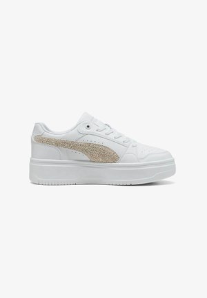 Sneaker bianca bassa con suola spessa e logo a strisce beige testurizzato sul lato. Chiusura con lacci e perforazioni vicino all'area della punta.