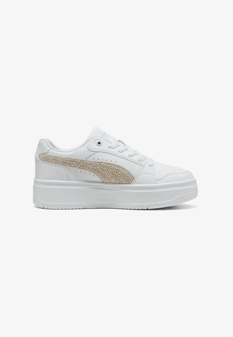 Baskets basses blanches avec semelle épaisse et logo rayé beige texturé sur le côté. Fermeture à lacets et perforations près de la zone des orteils.