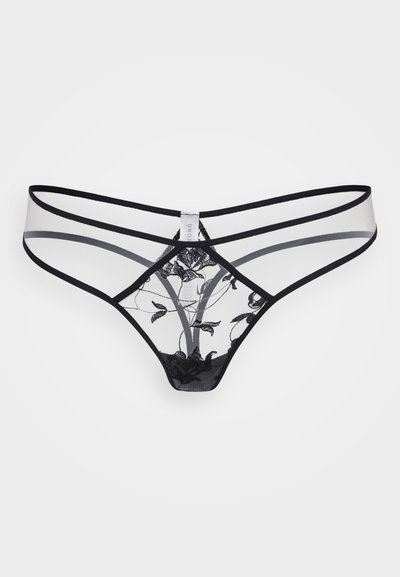 String en dentelle noire avec panneaux en tulle transparent, détails de broderie florale et sangles élastiques croisées. Étiquette visible au milieu du dos.