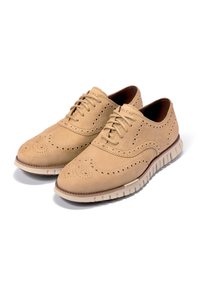 Krémové kožené společenské boty s brogue detaily, kulatou špičkou a lehkou, flexibilní podrážkou. Obsahují šněrovací design a texturovaný svršek.