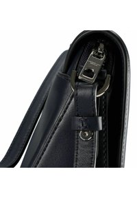 Borsa a mano in pelle blu navy con finitura liscia, accessori metallici e chiusura con zip. Cuciture dettagliate lungo i bordi e la tracolla.