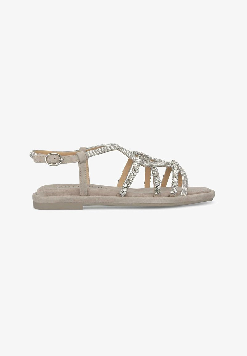 Beige Flachsandalen aus Wildleder-Textur mit silbernen Strassakzenten und einem Riemendesign. Verstellbarer Knöchelriemen mit Schnallenverschluss.