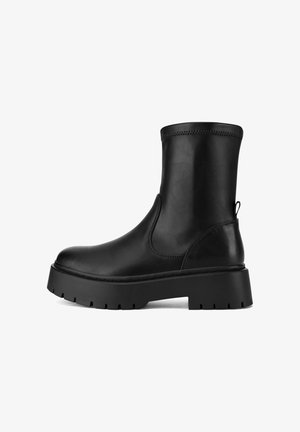 Botín negro de cuero liso. Cuenta con punta redondeada, paneles laterales elásticos y una suela gruesa con dibujo para mayor tracción.