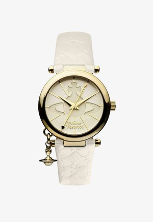 Goudkleurig horloge met een witte, geperforeerde leren band. De ronde kast heeft een gestructureerde crèmekleurige wijzerplaat met gouden accenten. Klein bedeltje hangt aan de band.