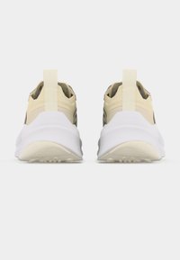 Ζευγάρι μπεζ και λευκά αθλητικά παπούτσια με παχιά σόλα, θηλιές στη φτέρνα και διακριτικό σήμα, από πίσω σε λευκό φόντο.