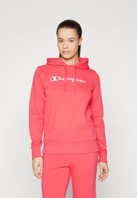 Felpa rosa con cappuccio e tasca frontale, con il logo "Champion" bianco. Realizzata in tessuto morbido con polsini e orlo a coste.