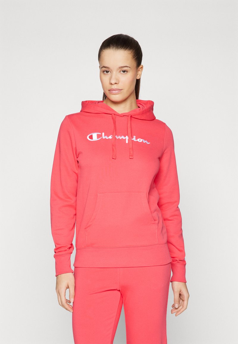 Felpa rosa con cappuccio e tasca frontale, con il logo "Champion" bianco. Realizzata in tessuto morbido con polsini e orlo a coste.