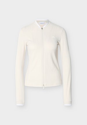 Light cream long-sleeve zip-up jacket with a fitted design, subtle wavy texture pattern, and white trim at the collar and cuffs.