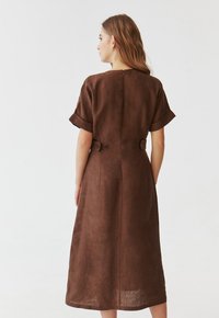Braun leinen Kleid mit kurzen umgeschlagenen Ärmeln, betontem Taillenbereich, Knopfdetails und einem knielangen A-linienförmigen Schnitt.