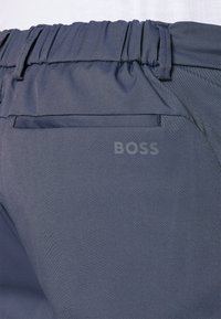Mørkegrå shorts laget av glatt stoff, med elastisk midjebånd og en baklomme med en subtil logo.
