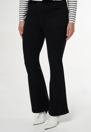 Zwarte flared jeans van denim, met een klassieke vijf-pocketontwerp en een gladde textuur, gecombineerd met witte pointy-toe laarzen.