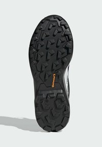 Schwarze Gummisohle mit tiefen Profilen, die ein markantes sechseckiges Muster aufweist. Enthält ein orangefarbenes "Continental"-Logo in der Mitte.