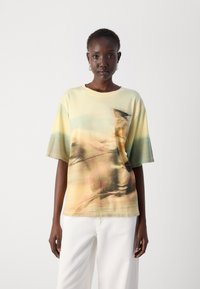 Cotton T-shirt with an abstract print in soft yellows and greens. Relaxed fit, short sleeves, crew neck, no visible tags or hardware details.