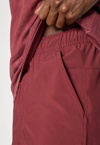 Bordeaux katoenmix shorts met een elastische tailleband en zijzak. De textuur is glad met een lichte glans en heeft een ontspannen pasvorm ontwerp.