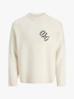 Kreminės spalvos megztinis su gipiūrinėmis rankovėmis ir apačia, kuriame yra juodas siuvinėjimas kairėje pusėje. Apvalus kaklas, laisvas siluetas.