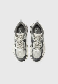 Sneakers atletici grigi e argento con tomaia in rete, dettagli riflettenti, lacci testurizzati e collo imbottito. Logo EA7 visibile.