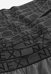 Schwarze und graue Boxershorts mit einem strukturierten Bund, der das Wort "NEXT" in fetten Buchstaben zeigt, und einem glatten, weichen Stofffinish.