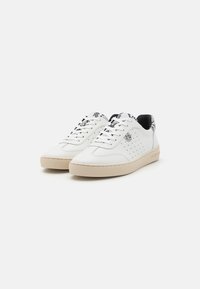 Sneakers bianchi in pelle con dettagli perforati, suola in gomma beige e accenti a motivi bianchi e neri sul tallone e sulla linguetta.