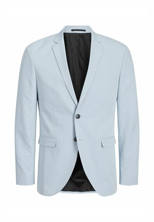 Hellblauer Anzug mit zwei Knöpfen, Stegkragen und Seitentaschen; kombiniert mit einem weißen T-Shirt und mehrfarbigen Sneakers.