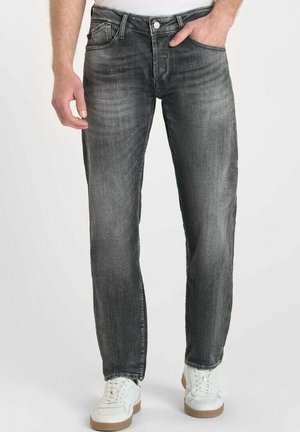 Grijze denim jeans met een rechte pijp, vijf zakken en subtiele vervaging. Gecombineerd met witte sneakers met een beige zool.