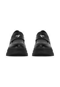 Zapatos negros de piel tipo mocasín con una correa ancha y un acento en forma de corazón plateado, que cuentan con una suela de goma gruesa para mayor altura.