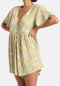 Grön blommig klänning med korta, fladdrande ärmar, djup V-ringning, knappar och fickor samt en avslappnad midja med rynkning.