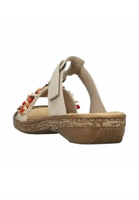 Beige sandaal met kleurrijke stenen accenten op de band, verstelbare klittenbandsluiting en een getextureerde rubberen zool voor grip.
