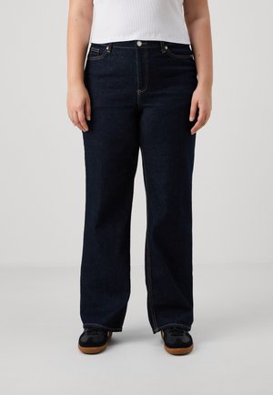 Dark blue wide-leg jeans with a high waist, featuring five pockets and visible stitching. Paired with black sneakers on a smooth surface.