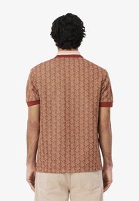 Brun mönstrad polo med korta ärmar och bourgognefärgad krage och muddar. Har en geometrisk design genom hela tyget.