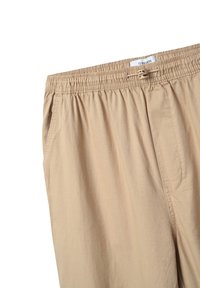 Pantaloni beige con vita elastica e tasche laterali, in tessuto leggero e fit rilassato. Dettagli cuciti lungo la vita e le cuciture.