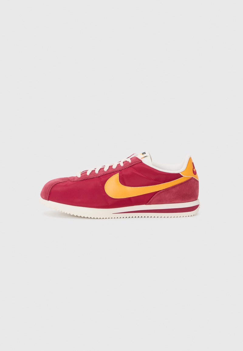 Baskets en suede rouge avec des accents jaunes, des lacets blancs et une semelle texturée. Design classique avec un bout arrondi et un détail de logo sur le côté.