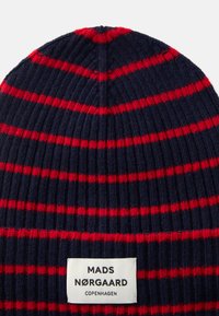 Beanie lavorato a maglia con strisce blu navy e rosse. Texture a coste con un'etichetta bianca con la scritta "MADS NØRGAARD COPENHAGEN" ricamata in fondo.