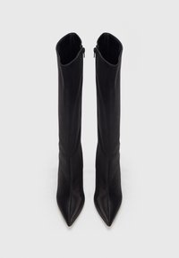 Cizme negre din piele, înalte până la genunchi, cu vârf ascuțit și textură netedă. Prezintă o închidere cu fermoar pe partea interioară a fiecărei cizme.