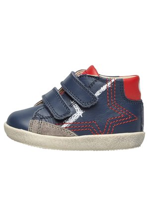Scarpa per bambino in pelle blu marina con dettagli rossi, cinturini in Velcro, design a stella bianca e toppa in suede grigia. Suola in gomma texturizzata.