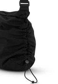 Černá látková taška s nashromážděným designem, vybavená stahovacím uzávěrem a hladkou texturou. Nastavitelný detail popruhu na vrchu.