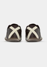 Sapatos de couro castanho com detalhes em creme e costura cruzada na parte de trás. Bico arredondado e sola texturizada para aderência. Design minimalista.