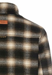 Geverfd flanellen shirt in zwart, bruin en wit. Heeft een opvallende kraag en een leren label met "Camel Active" op de achterkant.