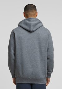 Felpa grigia con cappuccio regolabile, polsini e orlo a costine; realizzata in morbido materiale felpato; senza loghi o motivi visibili.
