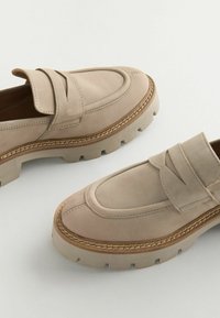 Bežové loafers vyrobené z hladkej kože majú dizajn mokasín, viditeľné prešívanie a masívnu gumovú podrážku pre lepšiu trakciu.