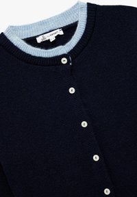 Dunkelblauer Cardigan mit einem hellblauen Rippkragen, der fünf weiße Knöpfe auf der Vorderseite aufweist. Weiches, texturiertes Strickmaterial.