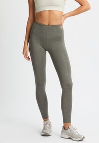 Leggings a vita alta di colore verde oliva con un motivo geometrico. Realizzati in materiale elasticizzato con una texture liscia, ideali per l'allenamento.