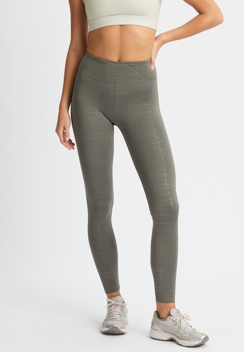 Leggings a vita alta di colore verde oliva con un motivo geometrico. Realizzati in materiale elasticizzato con una texture liscia, ideali per l'allenamento.
