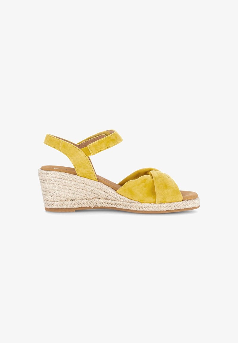 Sandale compensée jaune avec semelle en corde tressée, bout ouvert, bride avant nouée et bride de cheville réglable sur fond blanc.