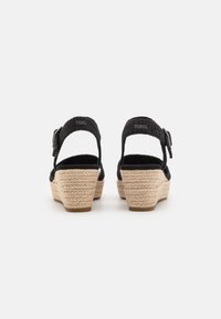 Wedge espadrilles nere con tomaia in tessuto texture, cinturino regolabile con fibbia e tacco in juta intrecciata, caratterizzate da una punta arrotondata.