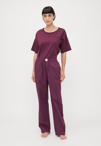 T-shirt violet à manches courtes avec col rond et pantalon ample assorti doté d'une taille élastique et d'une petite étiquette à l'avant.